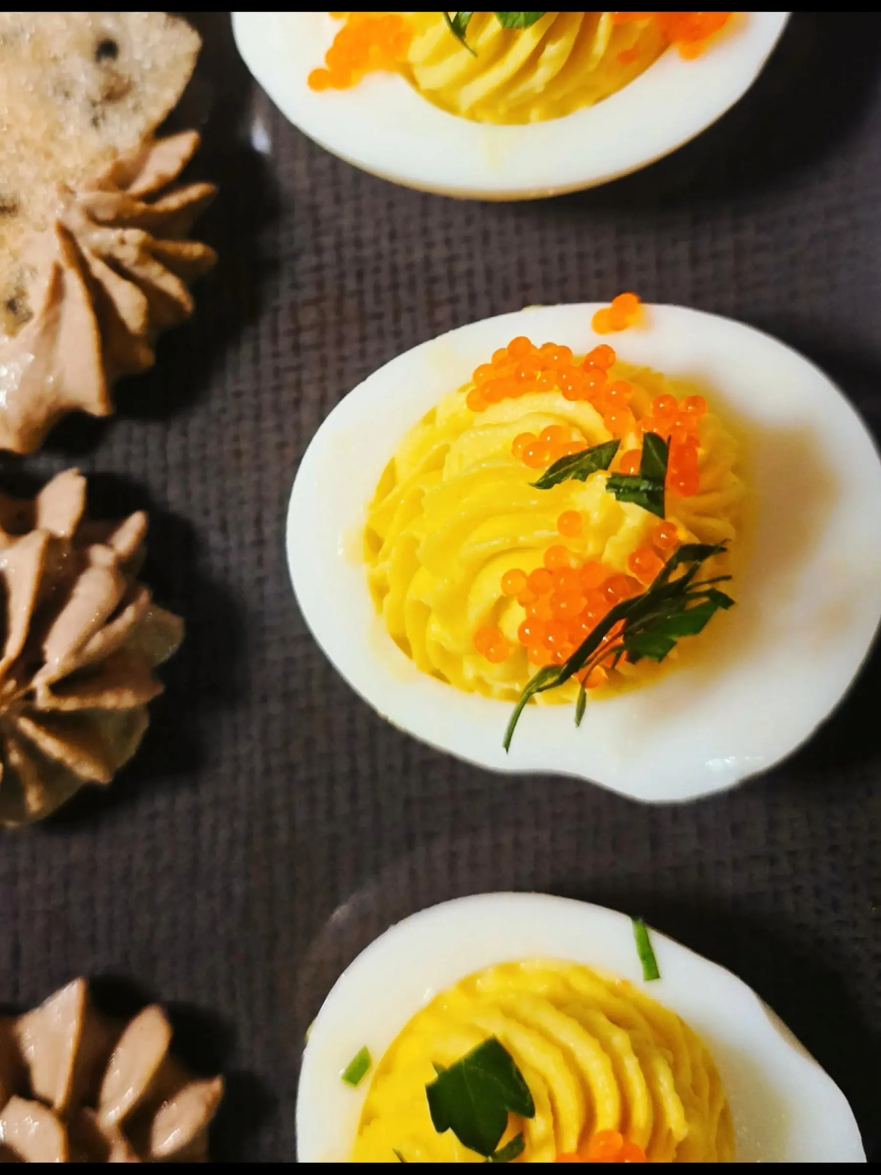 Deviled eggs piped high and topped with orange tobiko and fresh herbs